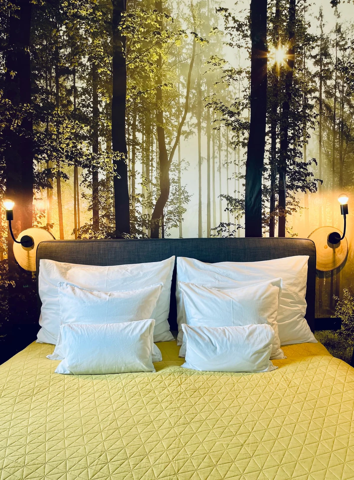 A bed with a forest mural and glowing wall lamps in a HYGGE apartment