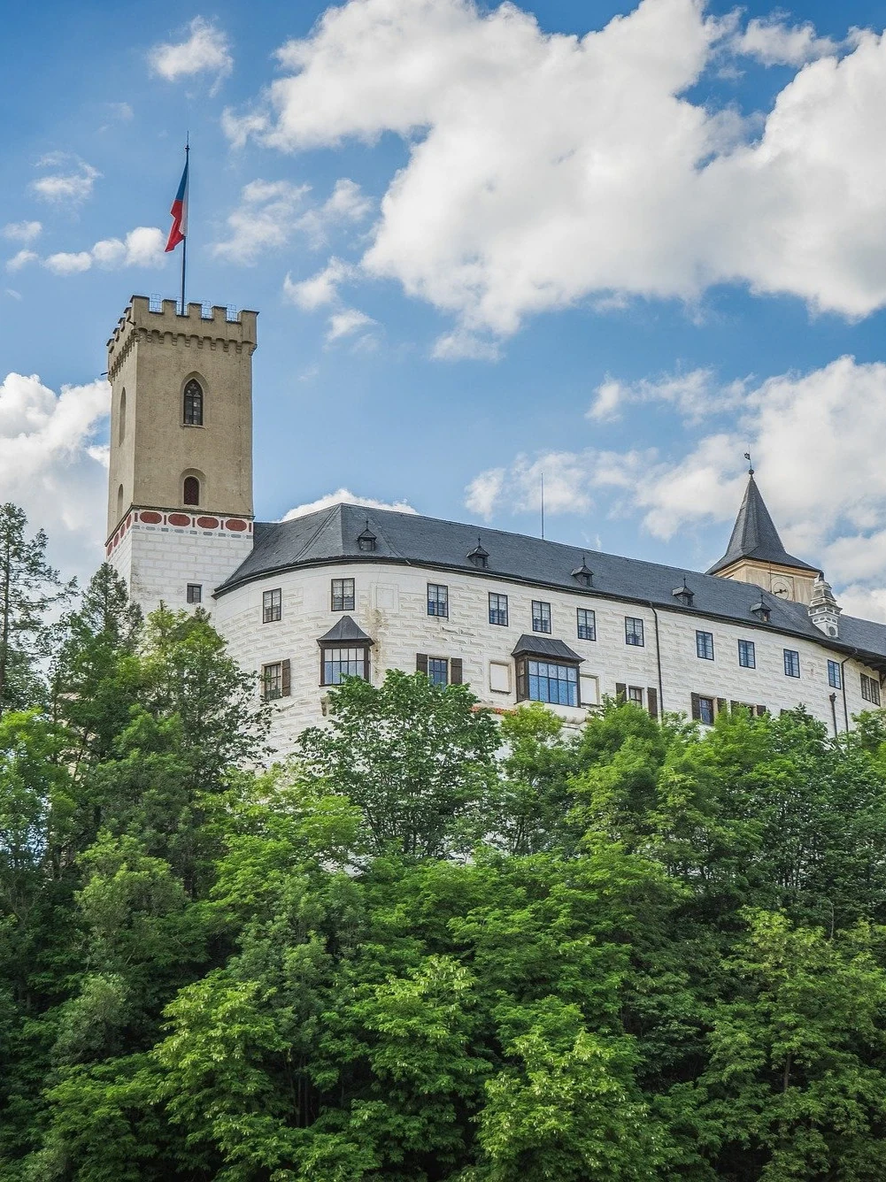 Rožmberk Castle and its white tower appearing above the treetops